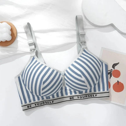 A striped blue and white nursing bra features adjustable shoulder straps with release clips and a bottom band printed with the phrase BE YOURSELF, displayed on a flat white surface.