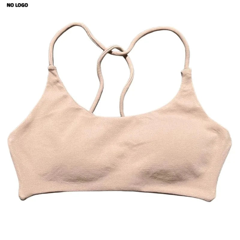 A beige sports bra featuring a scoop neckline, thin shoulder straps that cross at the back, and a seamless, minimal design set against a plain white background.