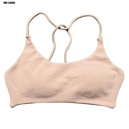 A beige sports bra featuring a scoop neckline, thin shoulder straps that cross at the back, and a seamless, minimal design set against a plain white background.
