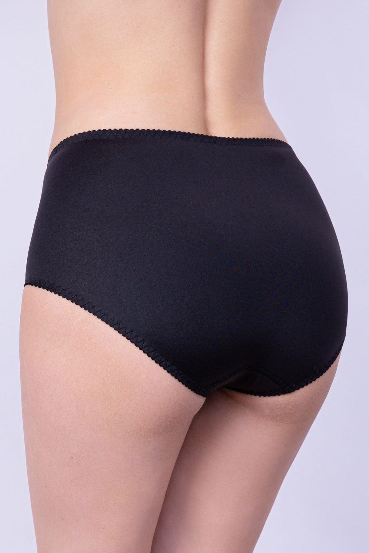 Black full-coverage briefs worn on a person, featuring a smooth fabric finish and delicate scalloped trim along the waistband and leg openings.