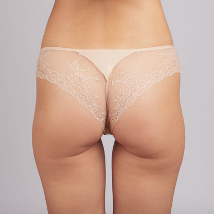 Beige lace thong underwear shown from behind on a person against a neutral background.
