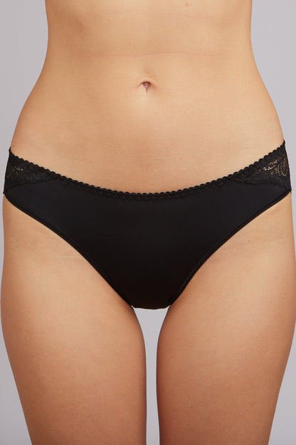 Black bikini-style panties with decorative scalloped lace trim on the sides and waistband, modeled on a person's torso.