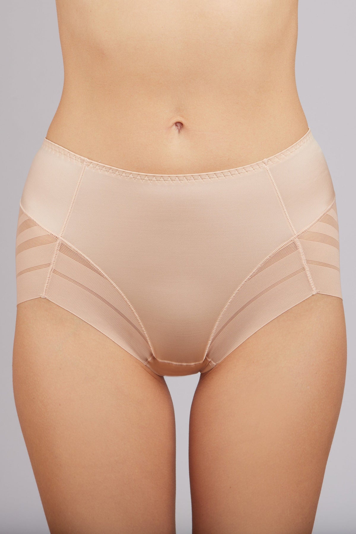 Nude-colored high-waisted briefs featuring side panel detailing with horizontal stitching against a plain light gray background.