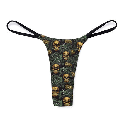 A thong featuring a repeating pattern of skulls nestled inside pineapples against a dark tropical leaf background with thin black side straps.