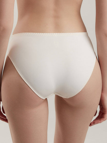 Off-white bikini-style panties with a visible zig-zag stitch pattern along the leg and waist edges shown from behind on a person.