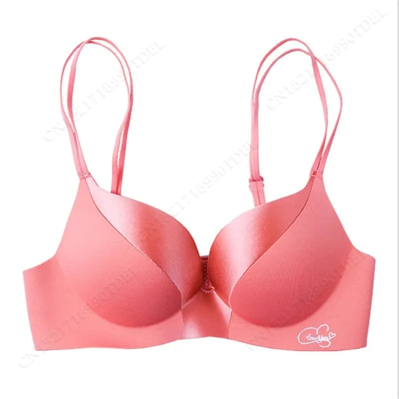 A seamless, coral-colored push-up bra with double spaghetti straps and a small white "Love You" emblem on the lower right cup.