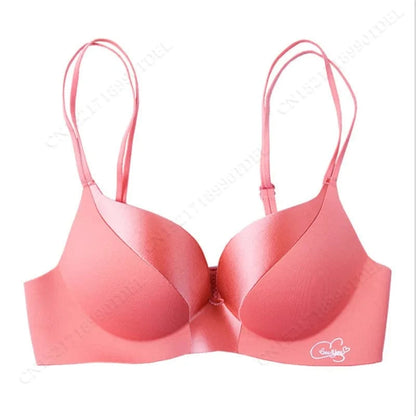 A seamless, coral-colored push-up bra with double spaghetti straps and a small white "Love You" emblem on the lower right cup.