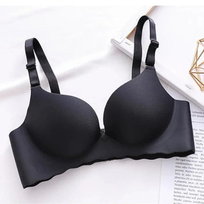 A black seamless underwire bra with thin adjustable straps lies against a white background.