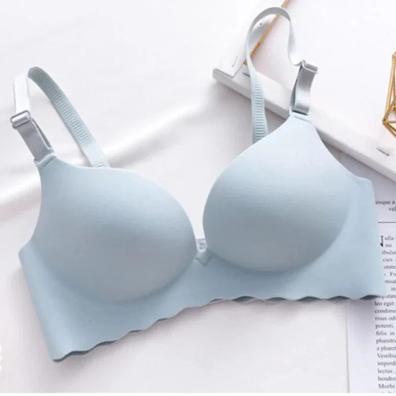 A light blue wireless bra with molded cups, adjustable shoulder straps, and a scalloped bottom edge displayed on a white surface.
