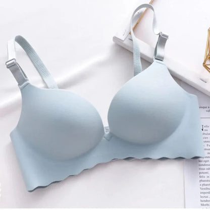 A light blue wireless bra with molded cups, adjustable shoulder straps, and a scalloped bottom edge displayed on a white surface.