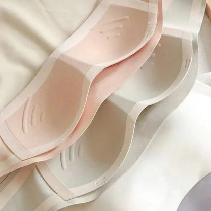 Two stacked seamless bra inserts in soft shades of pale pink and off-white feature molded cups with a curved, contoured design.