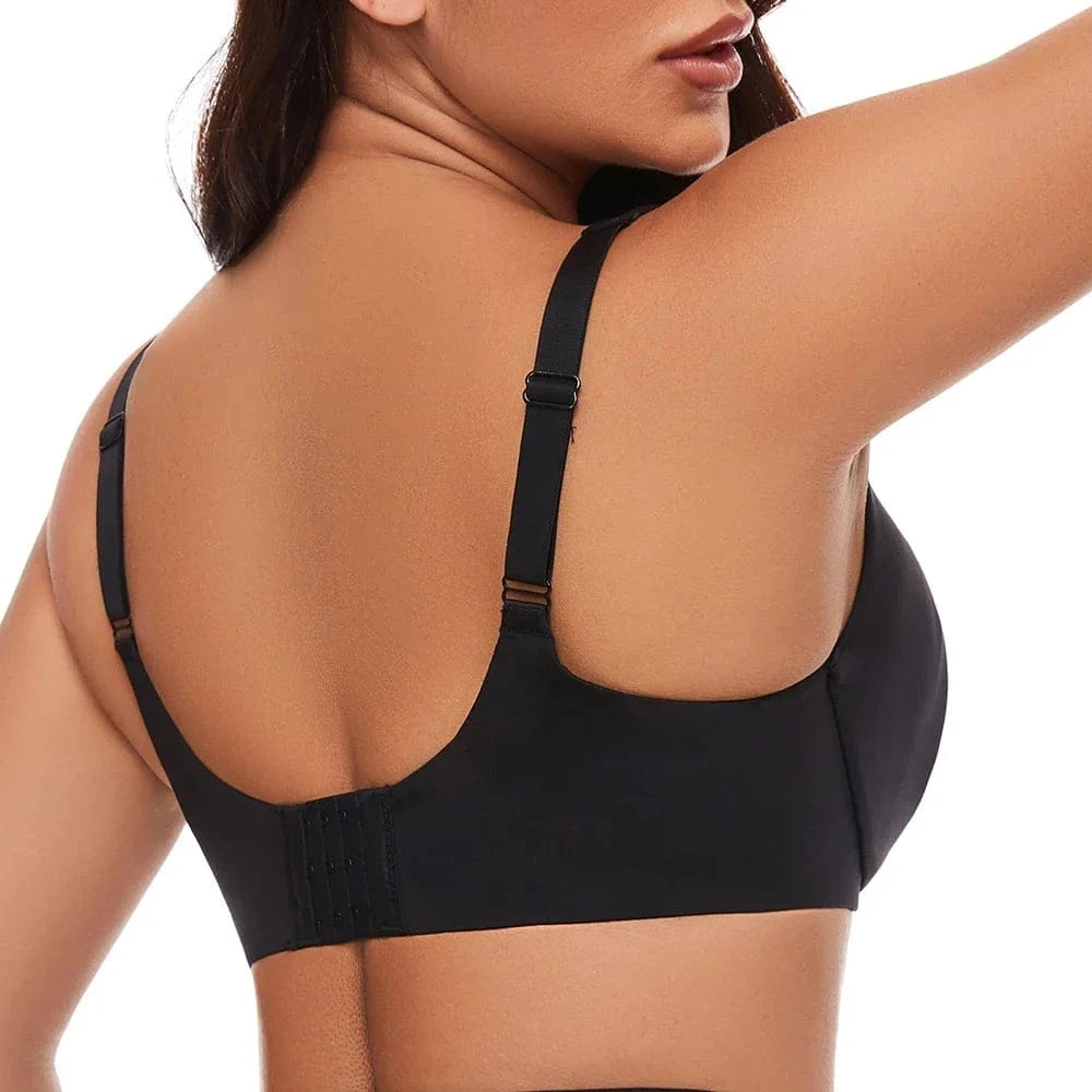 A back view of a person wearing a solid black bra with adjustable straps and a hook-and-eye closure.