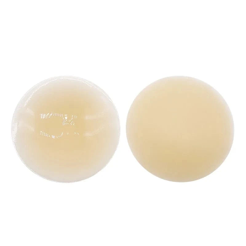 Two circular adhesive nipple covers in varying light skin tones are displayed side by side against a solid white background.