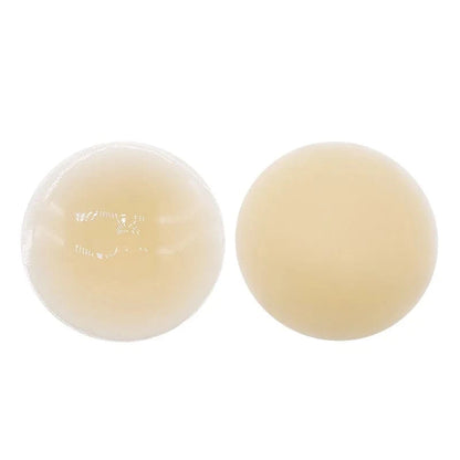 Two circular adhesive nipple covers in varying light skin tones are displayed side by side against a solid white background.