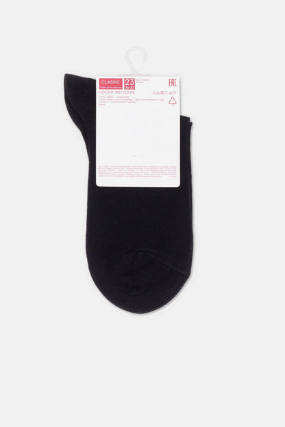 A pair of plain black ankle socks are displayed flat against a plain light gray background with a white cardboard product tag attached to the top.