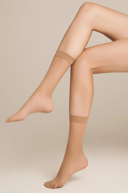 A pair of sheer nude-colored ankle socks shown on legs against a neutral background.