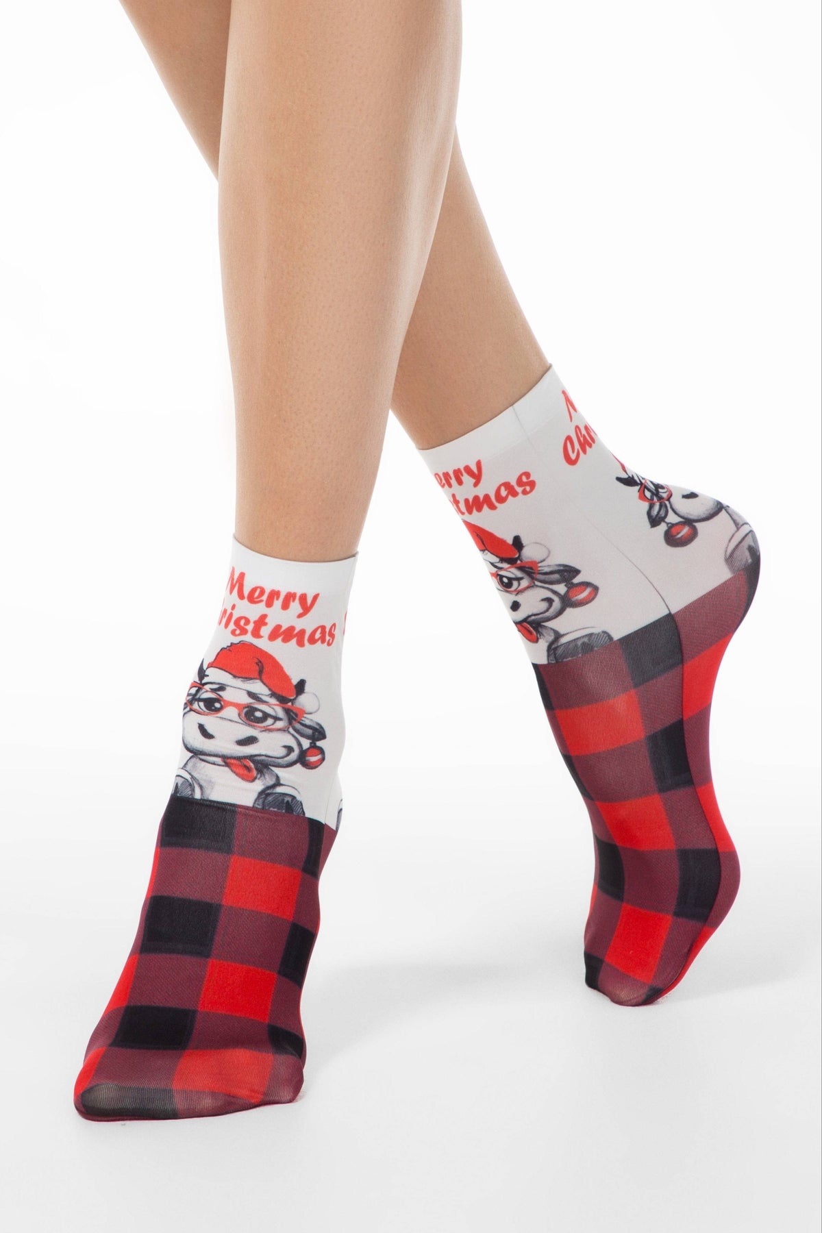 A pair of white ankle socks featuring a cartoon cow wearing a red Santa hat and glasses, accented with a red and black buffalo plaid pattern on the toes and heels.