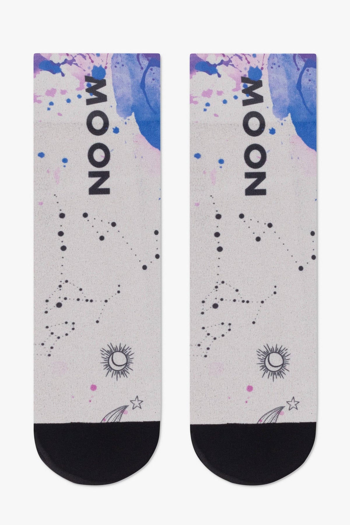 A pair of crew socks featuring a light grey background with a blue and purple watercolor wash, the word MOON printed vertically in black, and graphics of constellations, a sun, and a shooting star with a black toe section.