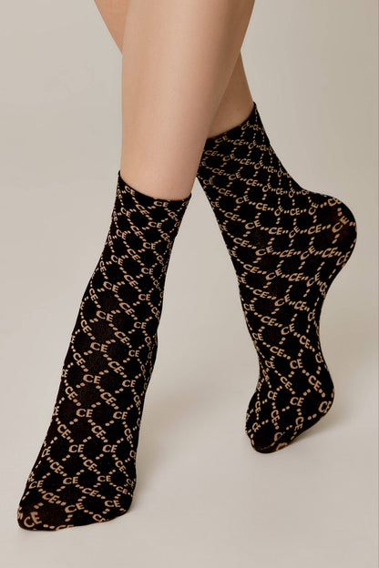 A pair of sheer black socks on a person's feet, decorated with a repeating pattern of light-colored CE logos connected by dashed lines.