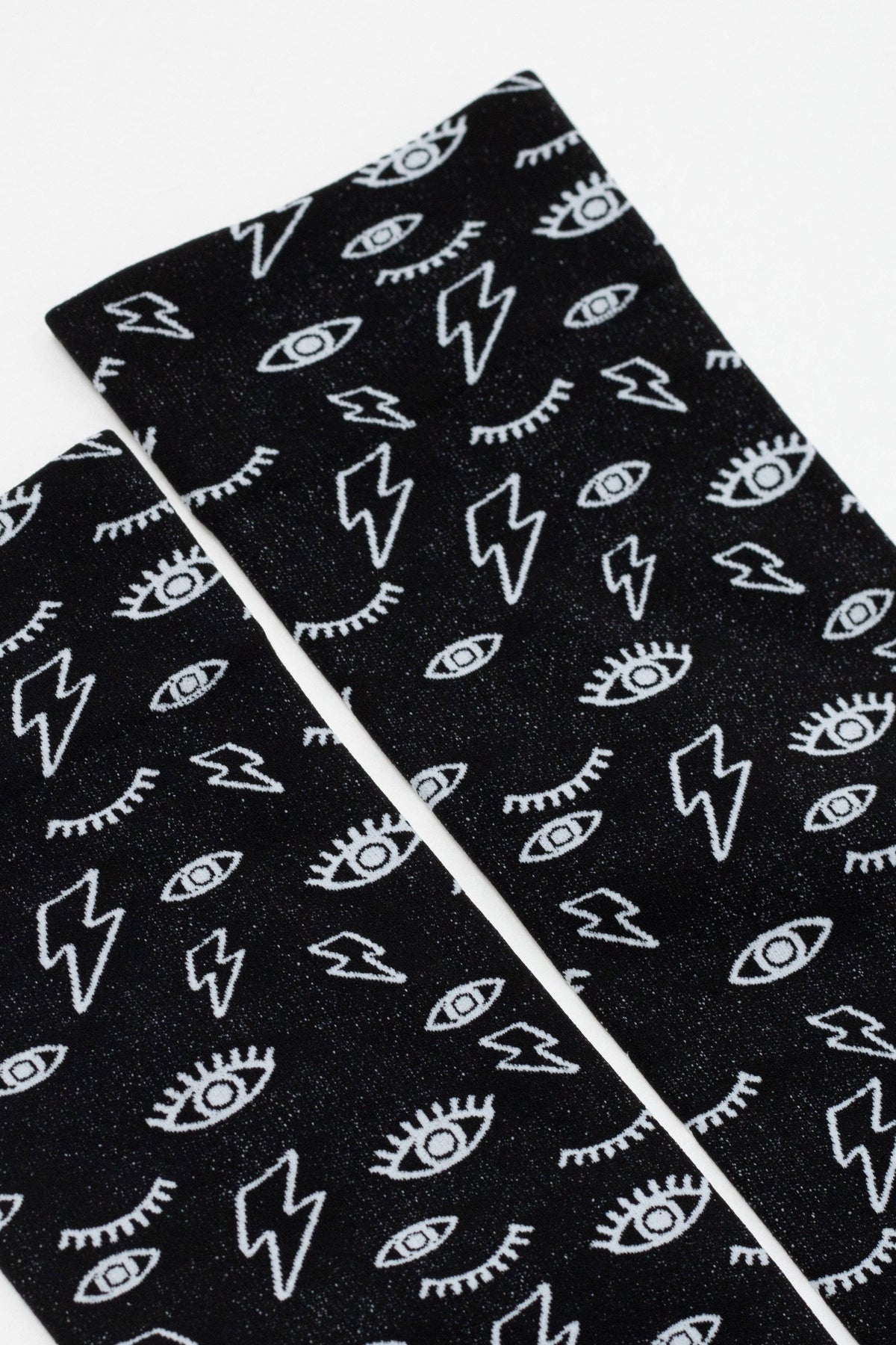 A pair of black socks featuring an all-over white graphic print pattern of lightning bolts and stylized eyes with eyelashes.