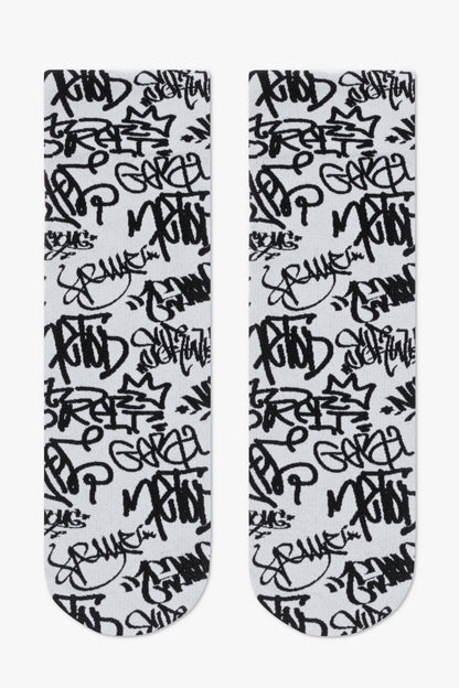 A pair of crew-length socks featuring a repeating black graffiti-style tag pattern on a light grey background.