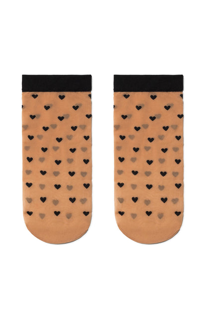 A pair of sheer, tan-colored ankle socks featuring a repeating pattern of small black hearts and finished with a solid black cuff at the top.
