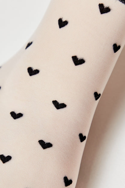 Sheer beige tights featuring a repeating pattern of small black hearts.