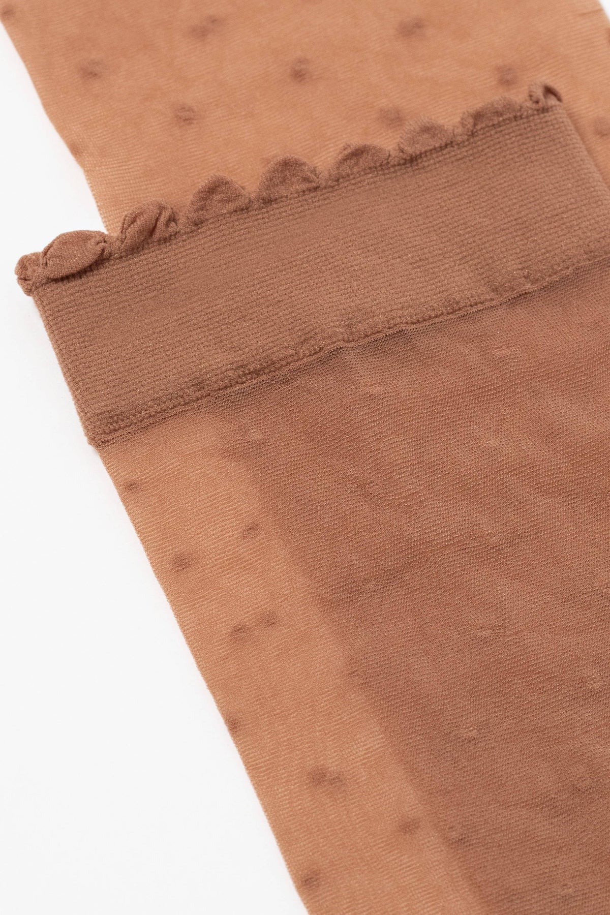 A close-up of a pair of brown sheer pantyhose featuring a delicate scalloped edge at the cuff and a subtle polka dot pattern.