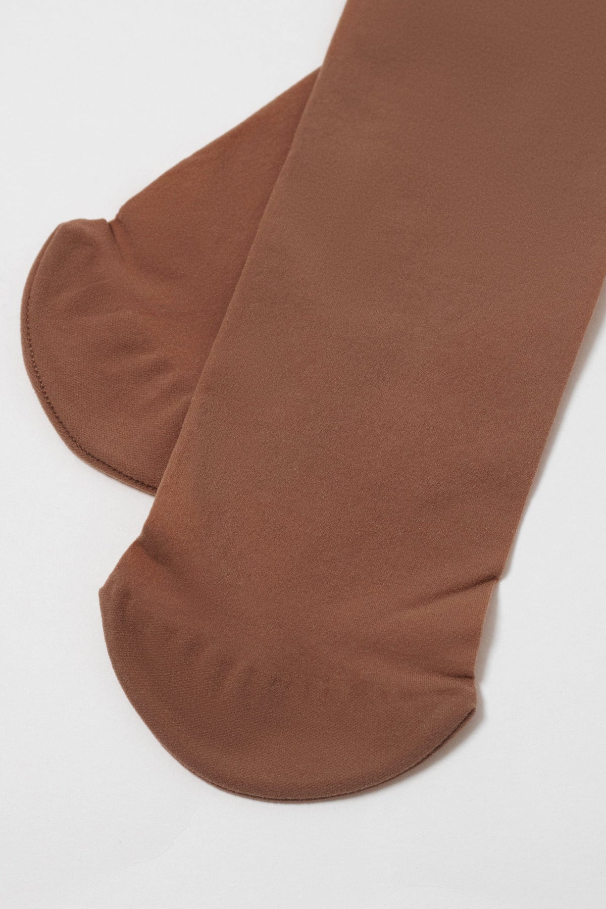 A pair of sheer brown stockings lying flat on a white surface, showing the rounded toe sections.