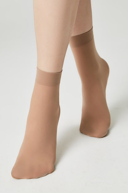 A pair of sheer, nude-colored ankle-length socks worn on a person's feet against a plain white background.