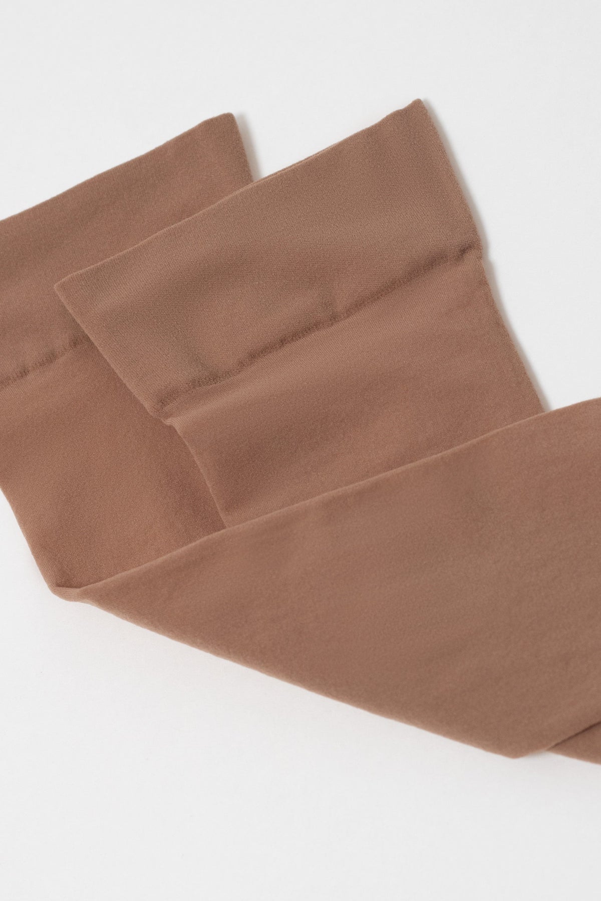 A pair of brown opaque tights folded against a plain white background.