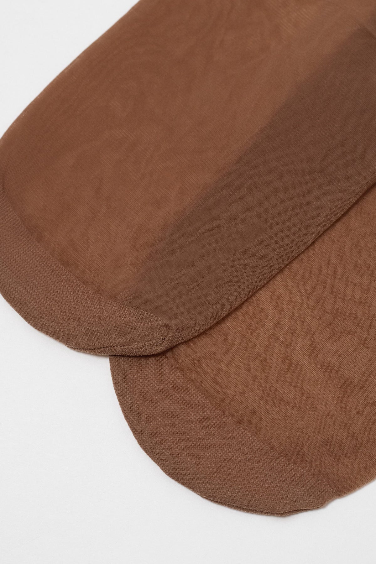 Two sheer, brown nylon stockings are laid flat against a white background, highlighting the reinforced toe sections.