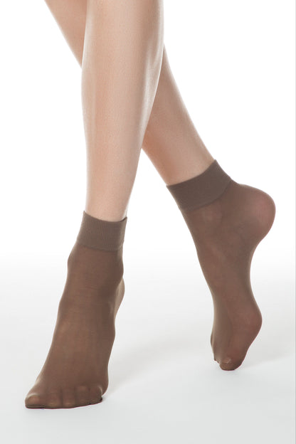 A pair of sheer, light brown ankle socks worn on a person's feet against a white background.