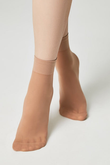 Nude-colored sheer ankle socks worn on a person's feet against a plain white background.