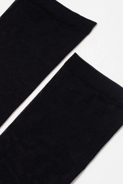 A pair of sheer black stockings laid flat against a plain white background.