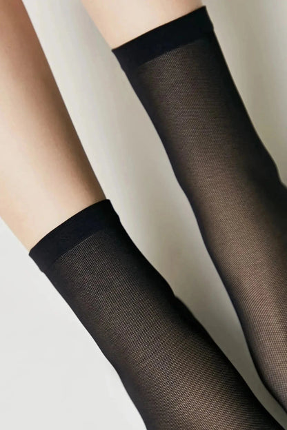 A pair of sheer black stockings shown on legs against a plain background.