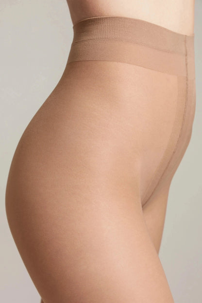 A close-up side profile of legs wearing sheer nude-colored pantyhose with a visible reinforced waistband and seam detail against a plain light background.