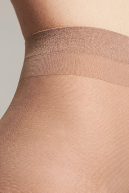 Nude-colored tights featuring a wide, reinforced waistband against a light neutral background.