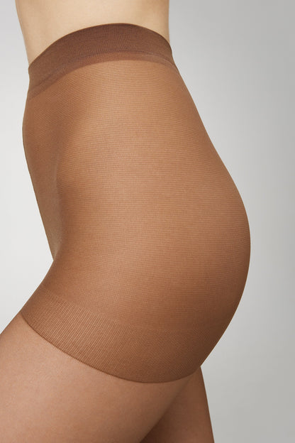 A close-up side view of a person wearing high-waisted, tan-colored sheer tights against a light grey background.