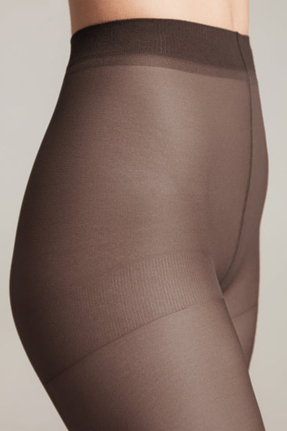 Sheer dark brown tights worn on a person, featuring a high-waisted waistband and a reinforced panty section.