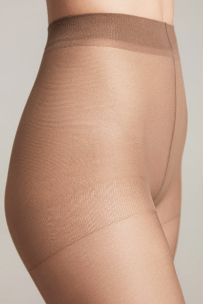 A close-up view of the side profile of a person wearing sheer beige pantyhose with a reinforced waistband and upper thigh area.