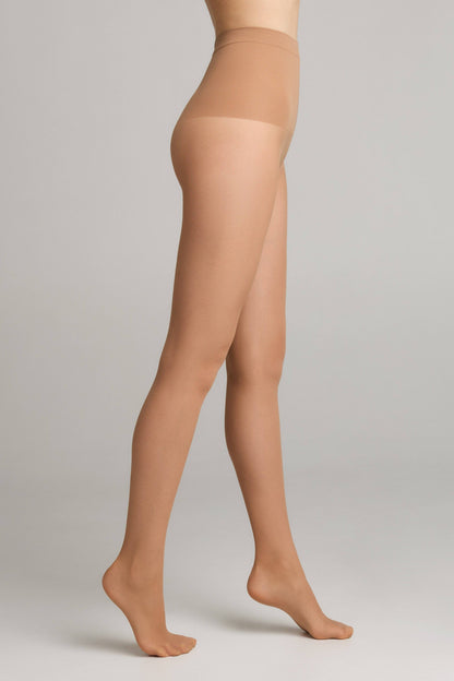 A person wearing sheer, light beige hosiery from the waist down, shown from a side profile against a plain grey background.