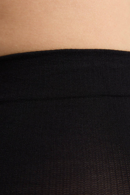 A close-up view of a black knit waistband resting against a person's skin.