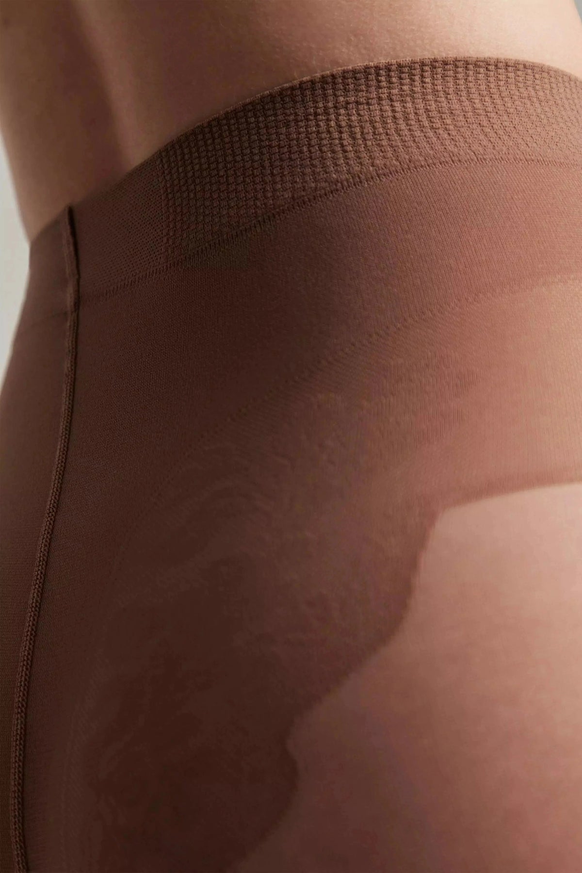 Sheer brown tights featuring a wide waistband and a reinforced panty area worn on a person's torso.