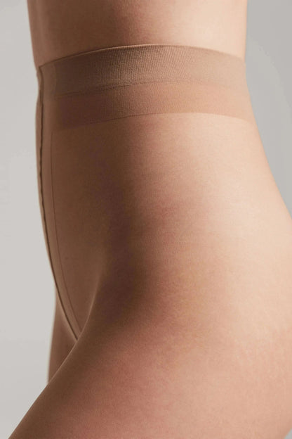 Nude-colored tights featuring a high-waisted design and a reinforced upper panel against a plain grey background.