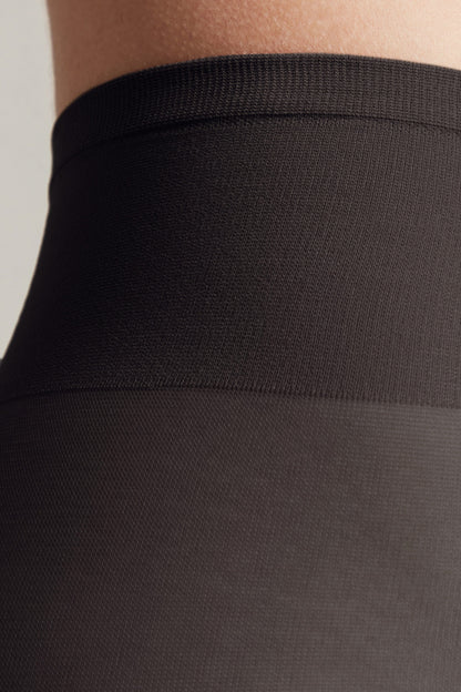 A close-up view of the black elastic waistband of a garment, showing the transition between the ribbed top band and the smoother opaque fabric below.