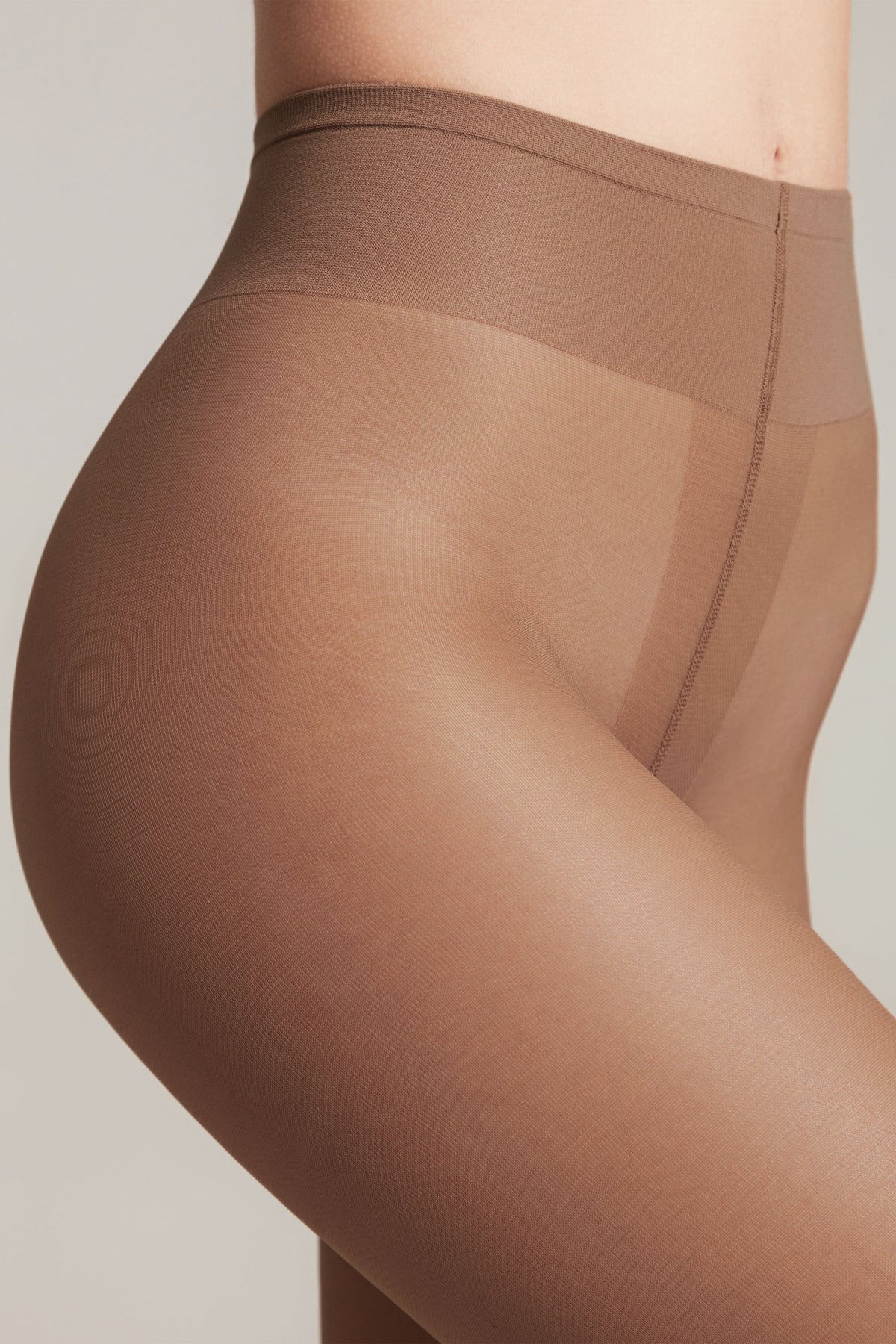 Nude-colored tights on a person's lower torso and hip, shown from a side profile against a plain, light background.