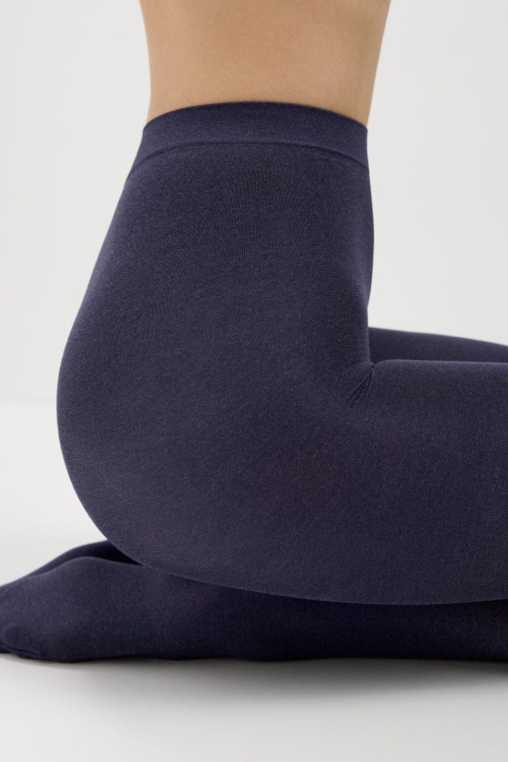 A pair of dark navy blue leggings worn by a person kneeling on a white surface.