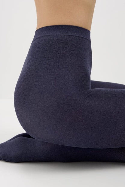A pair of dark navy blue leggings worn by a person kneeling on a white surface.