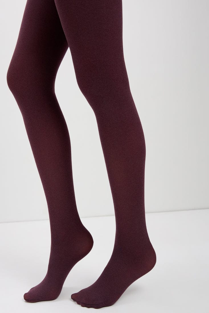 A pair of opaque maroon tights worn on a person's legs against a plain white background.